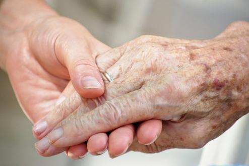 Nahaufnahme zweier Hände, eine ältere und eine jüngere, die sich liebevoll halten.